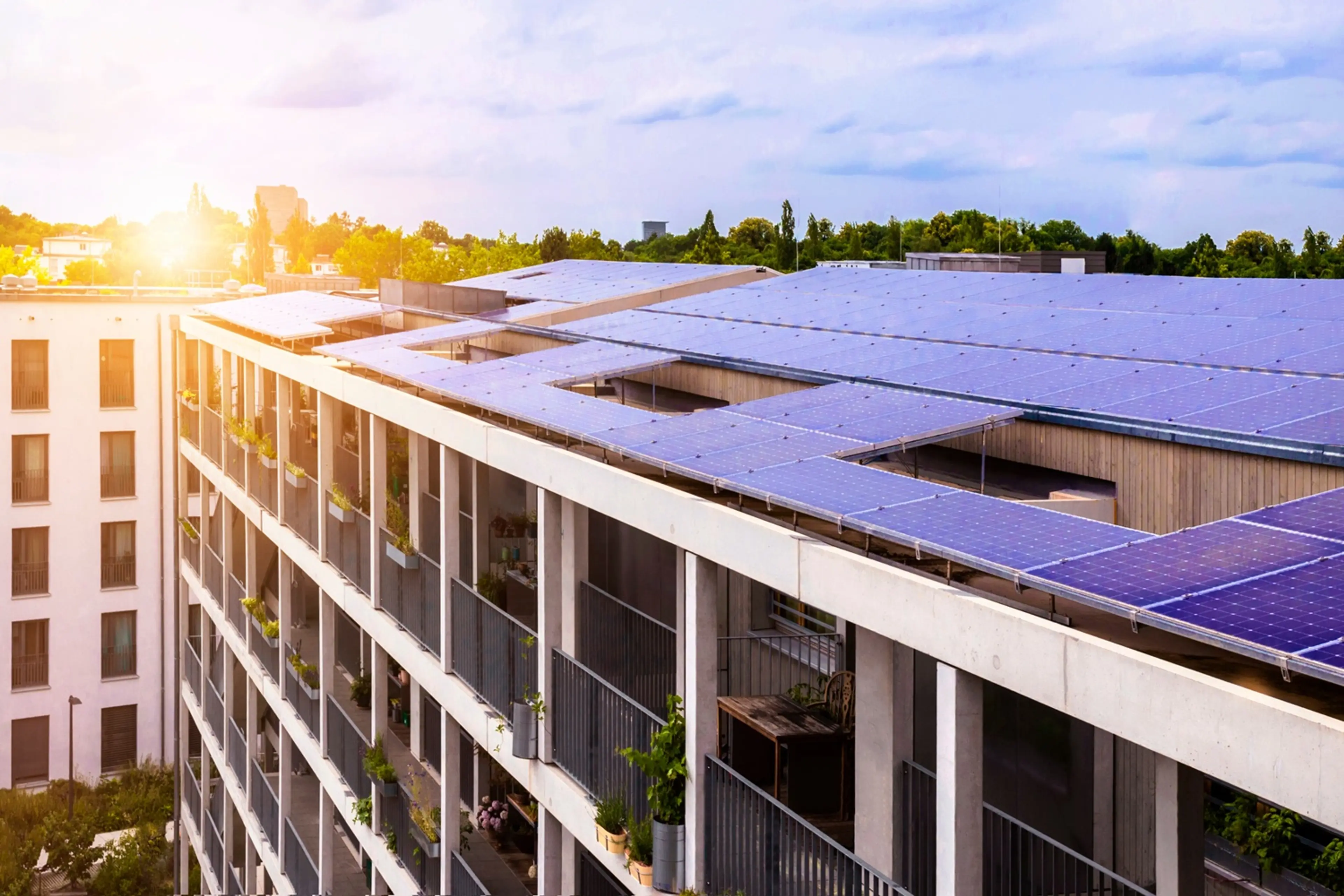 Moderne Häuser mit PV-Modulen auf dem Dach, im Hintergrund scheint die Sonne