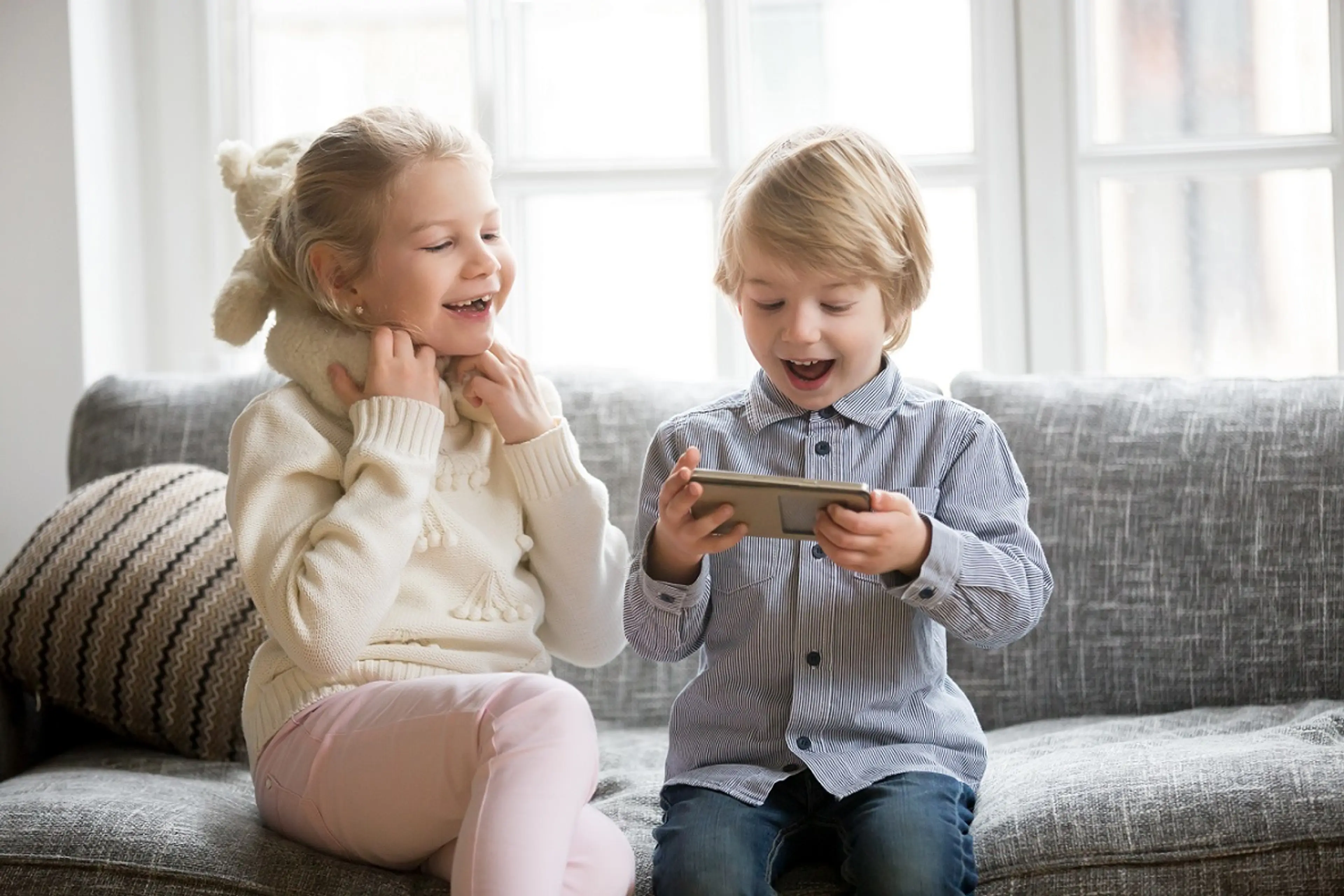 Mädchen und Junge auf dem Sofa mit einem Smartphone