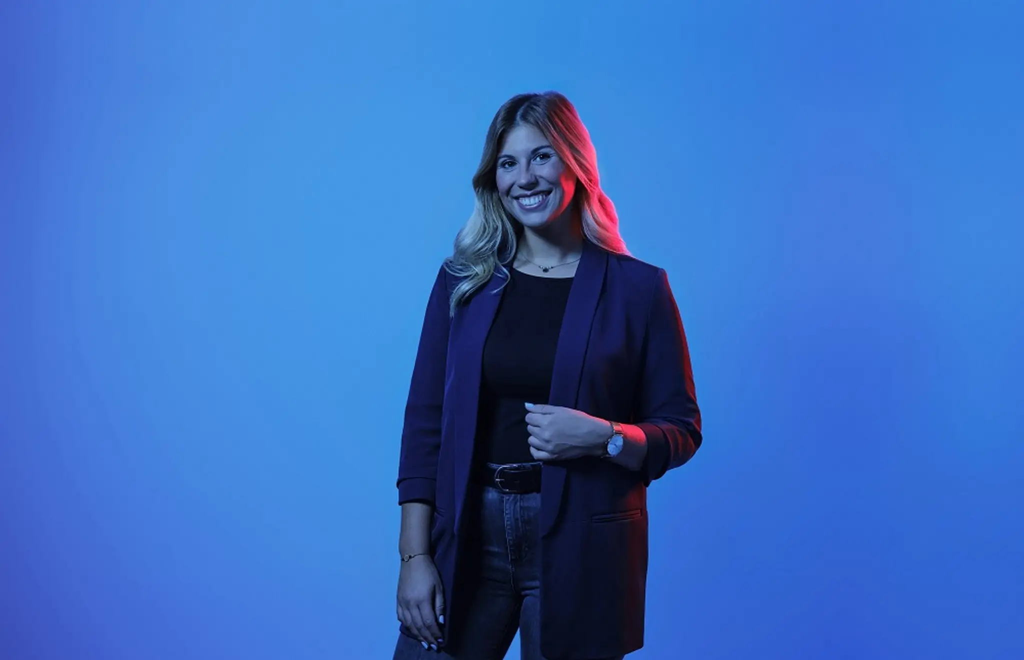 Eine Frau steht vor einem blauen Hintergrund und blickt in die Kamera