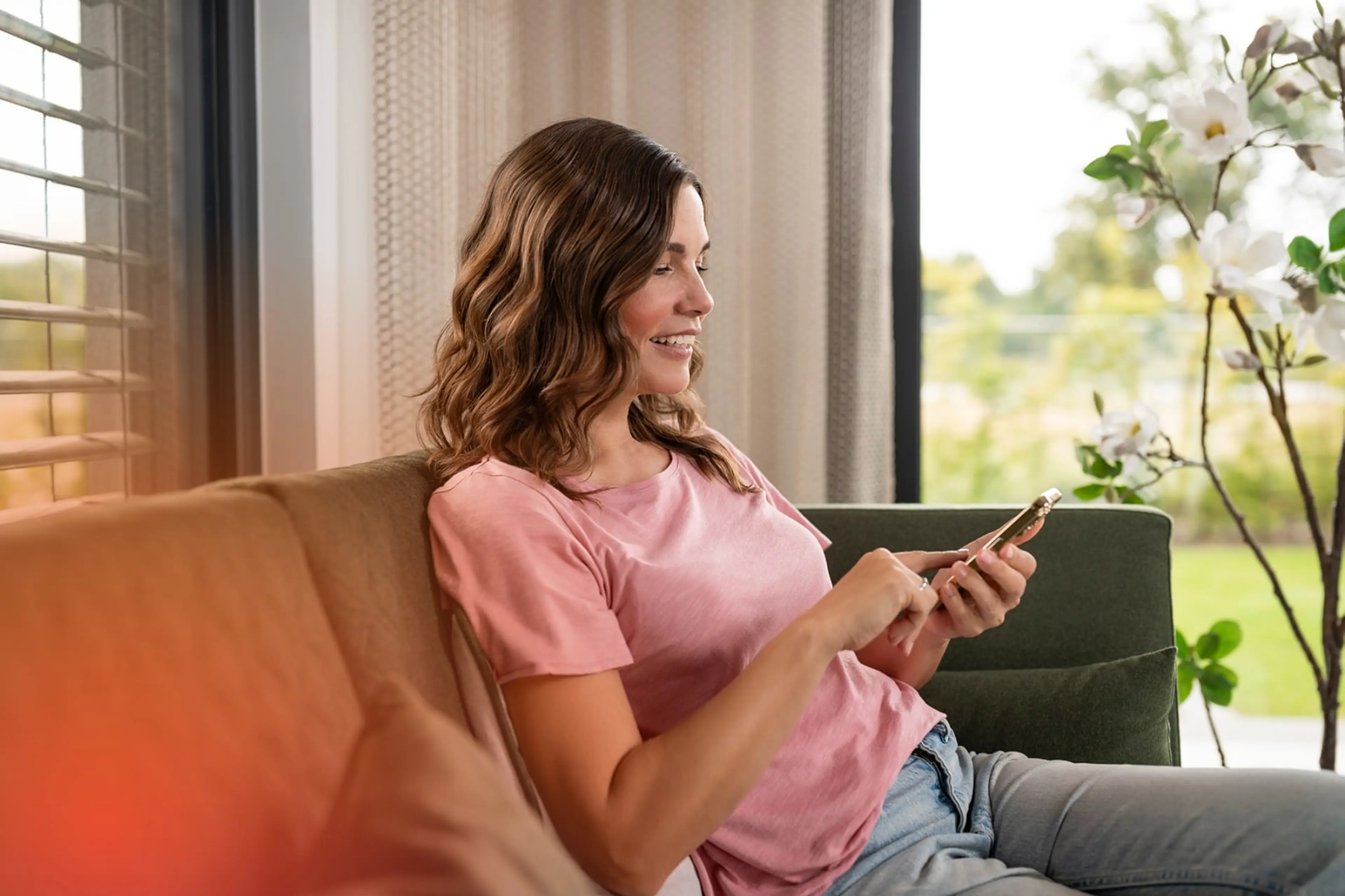 Hausanschluss anmelden | enercity Netz Eine Frau sitzt auf dem Sofa und schaut auf ihr Smartphone