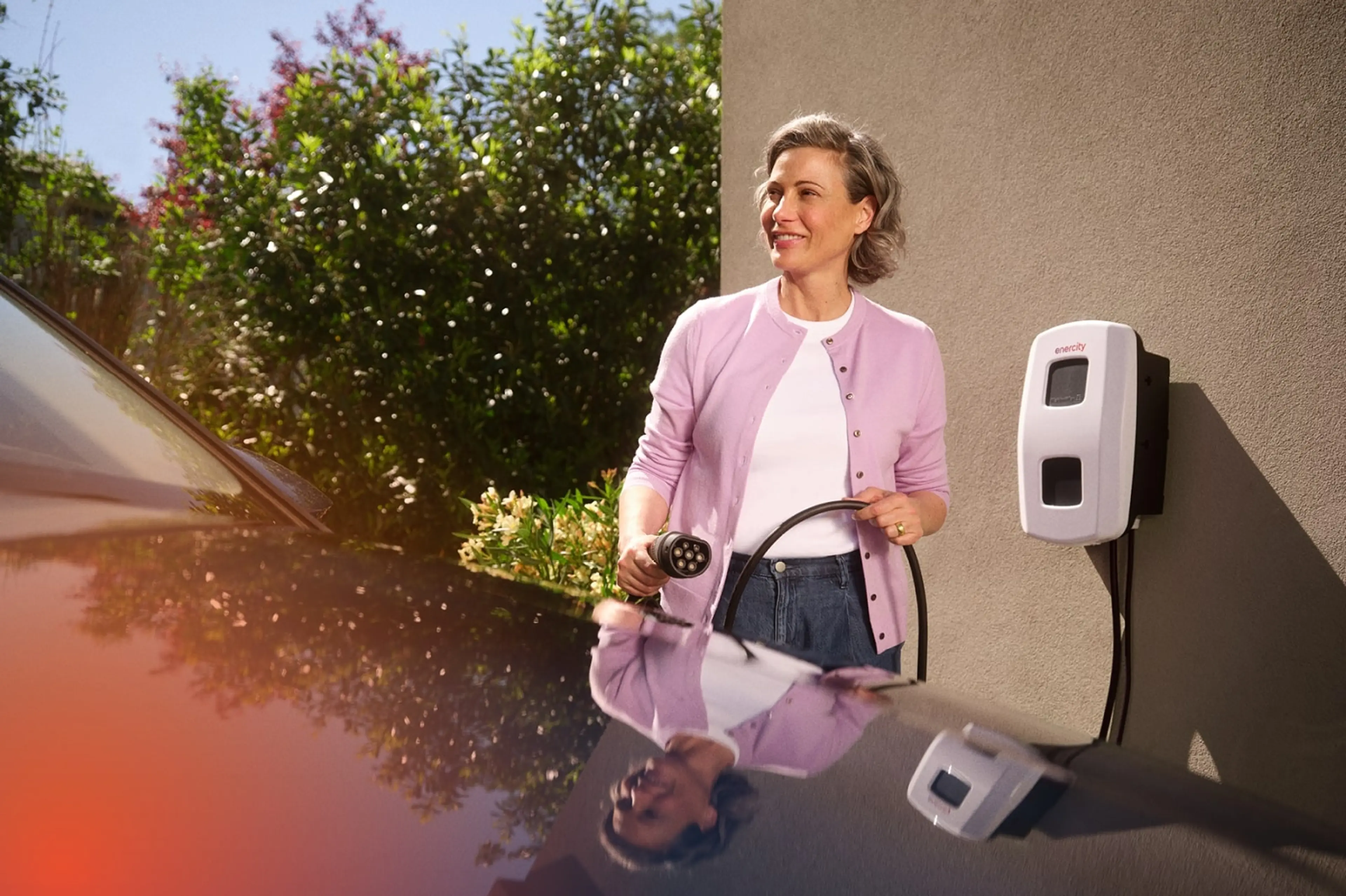 Ladeeinrichtung anmelden | enercity Netz Eine Frau steht hinter einem Auto und hält ein Ladekabel in der Hand