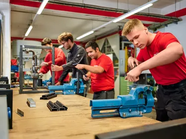 Mehrere Personen arbeiten handwerklich an Maschinen