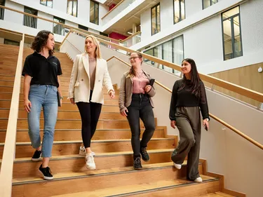 Mehrere Personen laufen die Treppe eines modernen Gebäudes hinunter